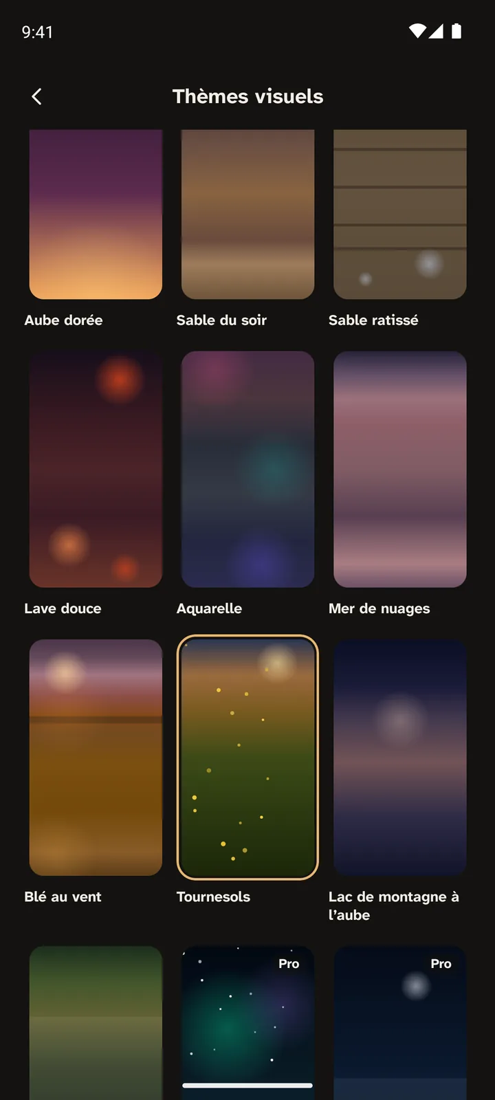 L'écran Thèmes visuels : une grille de fonds vivants, Aube dorée, Sable du soir, Sable ratissé, Lave douce, Aquarelle, Mer de nuages, Blé au vent, Tournesols, choisi et entouré d'or, et Lac de montagne à l'aube, puis deux fonds marqués Pro.